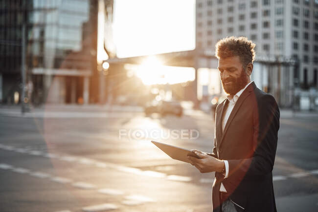 Empresario barbudo usando tableta digital en día soleado - foto de stock