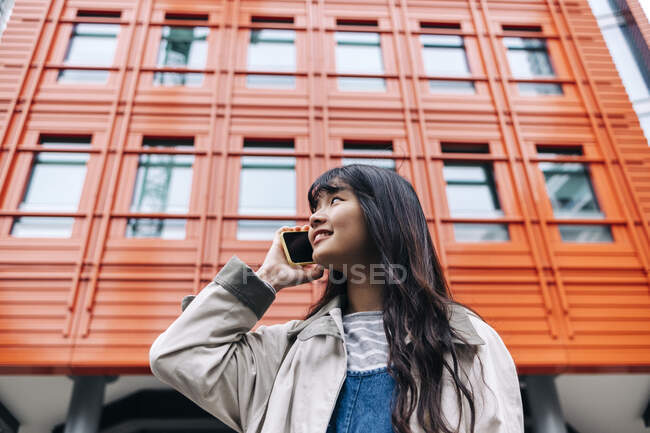 Giovane donna che parla sul cellulare di fronte all'edificio — Foto stock
