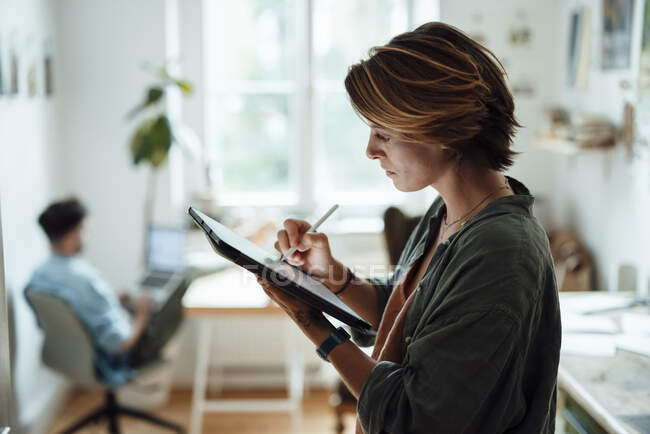 Empresaria que usa tableta gráfica mientras trabaja en casa - foto de stock