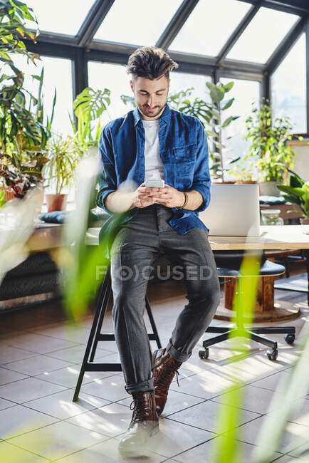 Giovane uomo d'affari che naviga in rete attraverso smart phone in ufficio — Foto stock