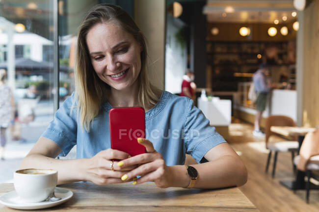 Freelancer feminino usando telefone inteligente enquanto está sentado na cafeteria — Fotografia de Stock