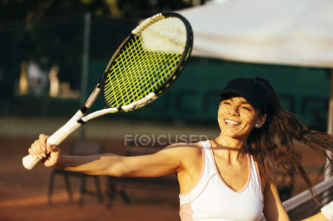 Felice atleta donna con racchetta che gioca a tennis al campo sportivo — Foto stock