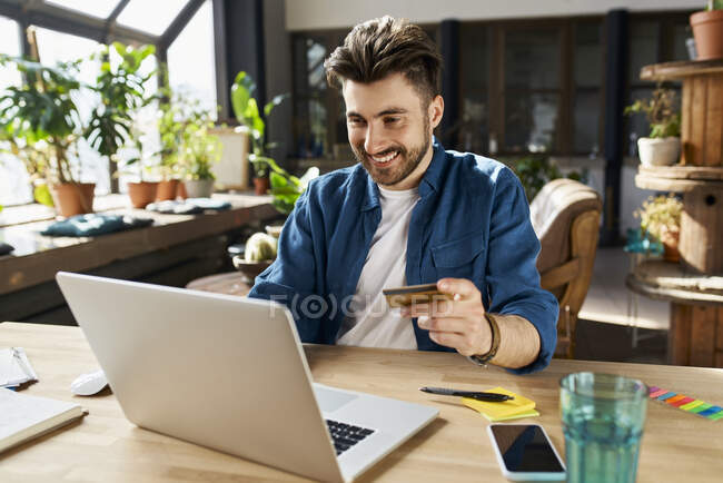 Male professional with credit card doing online shopping in office — Stock Photo