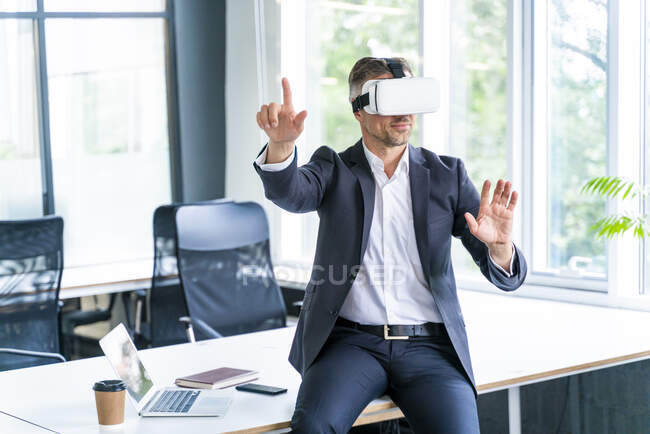 Hombre de negocios profesional con auriculares de realidad virtual gestos en la oficina - foto de stock