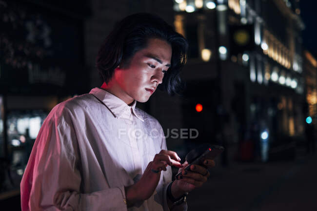 Bello giovane uomo che naviga in rete attraverso il telefono cellulare in città — Foto stock