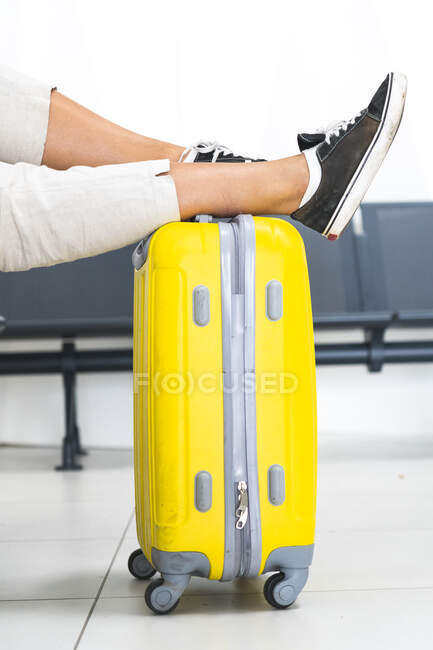 Woman leaning legs on luggage at airport departure area — Stock Photo