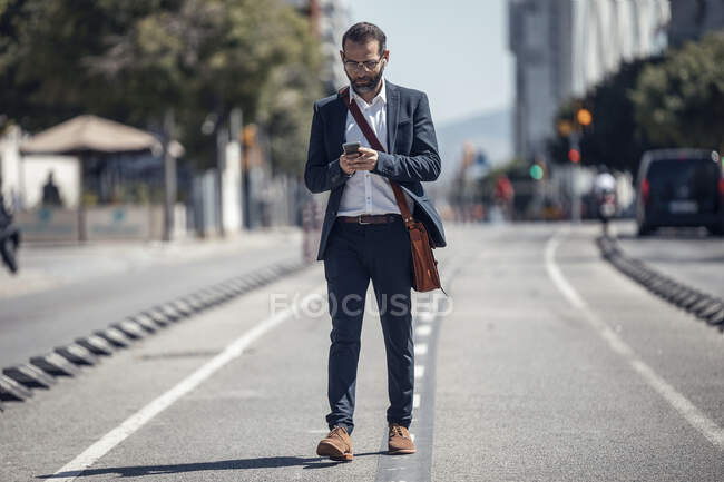 Hombre de negocios profesional utilizando el teléfono móvil mientras camina en la ciudad — Stock Photo