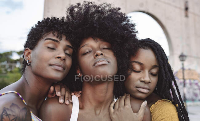 Jeunes femmes les yeux fermés s'appuyant sur les épaules d'une amie — Photo de stock