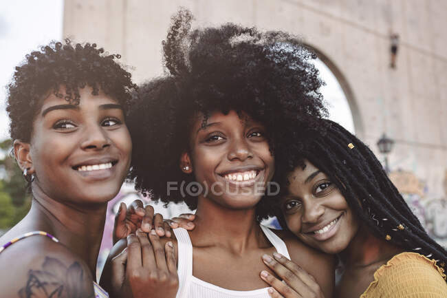 Sonrientes amigas jóvenes apoyadas en la mujer - foto de stock