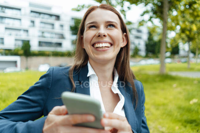 Щаслива жінка-фрилансер з розумним телефоном у громадському парку. — стокове фото