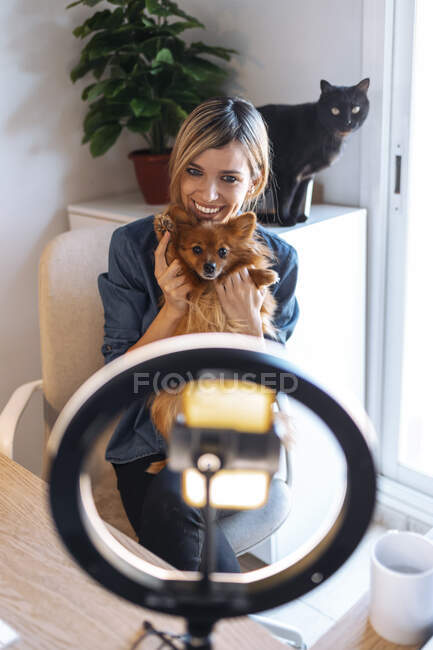 Lächelnde Vloggerin mit Hund zu Hause — Stockfoto