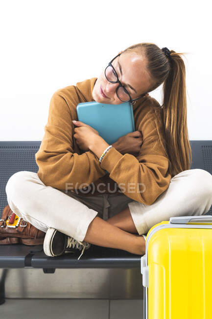 Mulher segurando comprimido digital enquanto sentado de pernas cruzadas no banco — Fotografia de Stock