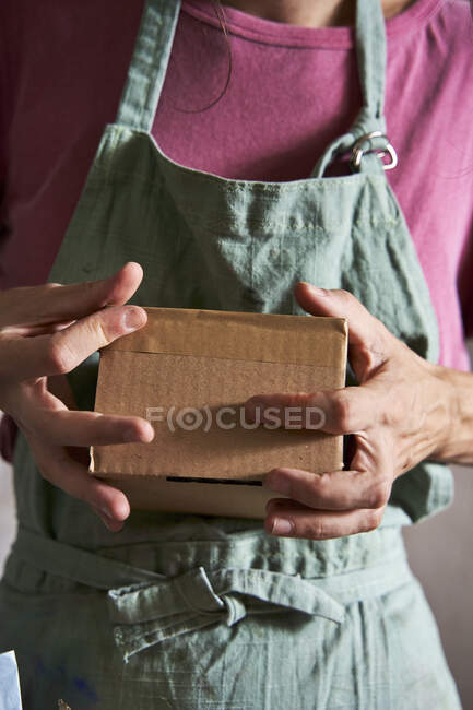 Female design professional packing cardboard box while working in workshop — Stock Photo