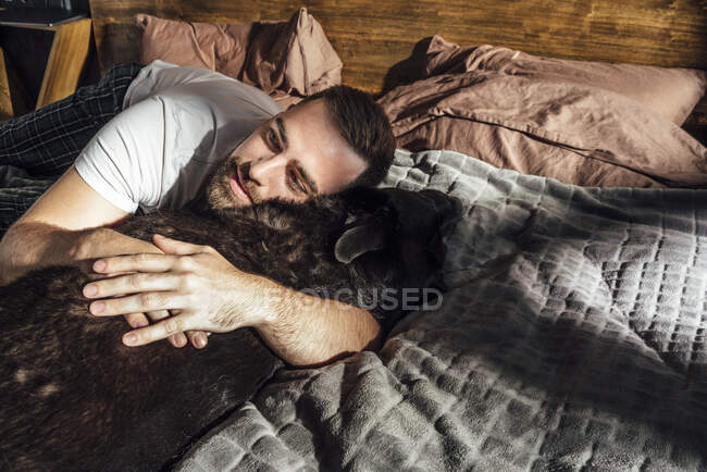 Доросла людина обіймає собаку на ліжку. — стокове фото
