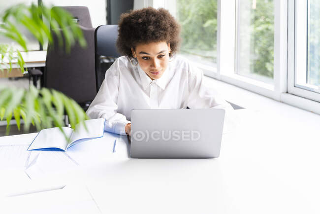 Professionnel féminin d'affaires utilisant un ordinateur portable tout en travaillant dans le bureau — Photo de stock