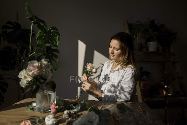 Mujer arreglando flores en la mesa - foto de stock