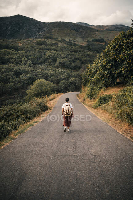 Femme mûre portant un sac à dos marchant sur la route — Photo de stock