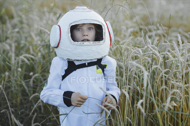 Cute boy wearing space suit and helmet at field — Stock Photo