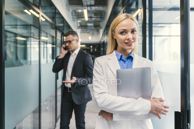 Femme d'affaires avec un collègue masculin debout dans le couloir au bureau — Photo de stock