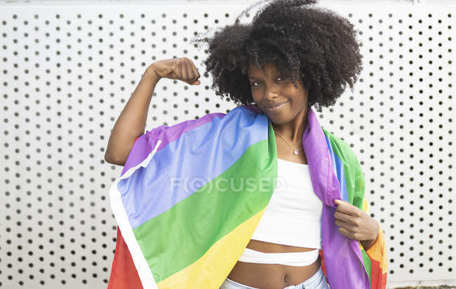 Afro lesbiana mujer flexionando los músculos delante de la pared - foto de stock