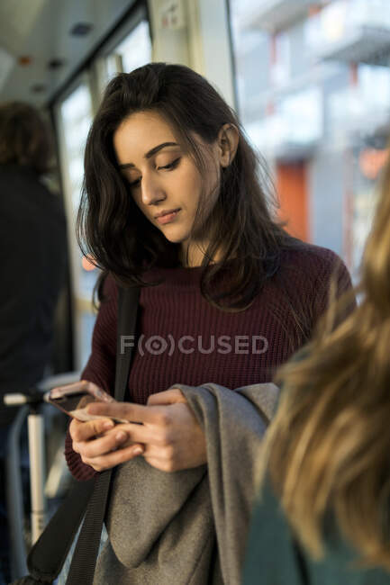 Woman using smart phone while travelling in tram — Stock Photo