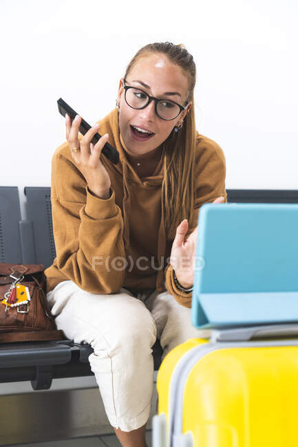 Жінка махає рукою під час відеодзвінка, хоча цифровий планшет на території виїзду з аеропорту — стокове фото