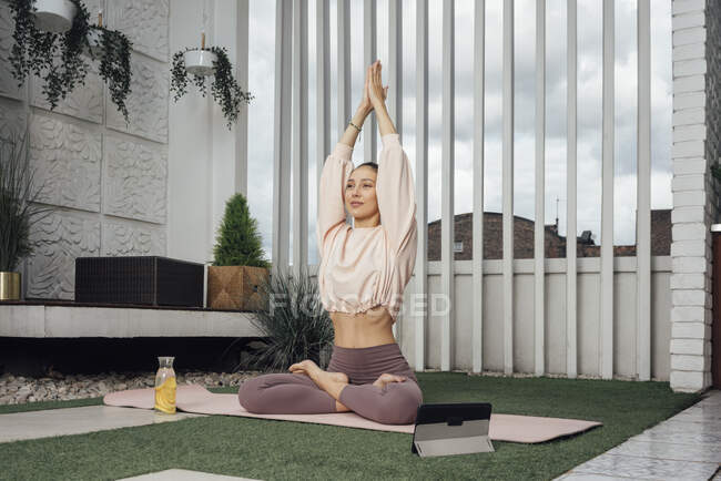 Femme moyenne adulte avec tablette numérique pratiquant le yoga sur la terrasse — Photo de stock