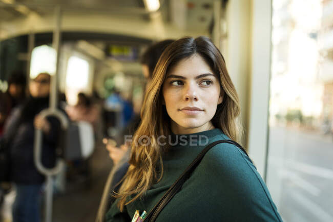 Jovem mulher olhando através da janela enquanto viaja em bonde — Fotografia de Stock