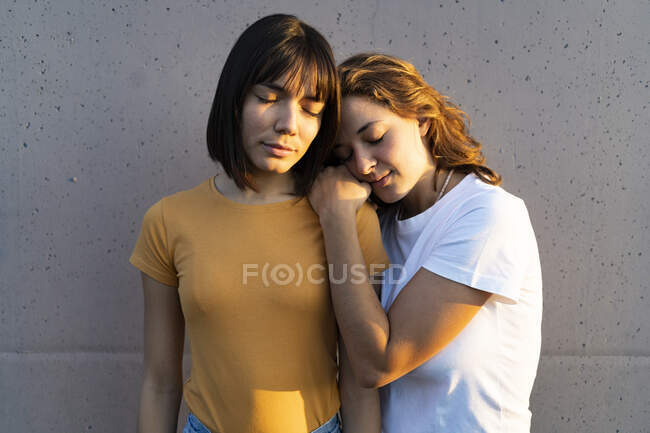 Coppia lesbica con gli occhi chiusi davanti al muro grigio — Foto stock