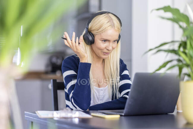 Maturo femmina freelance gesturing durante video chiamata su laptop a casa ufficio — Foto stock