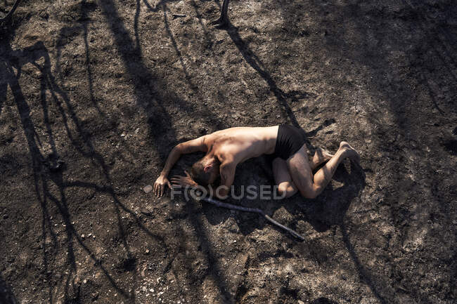 Uomo solitario sdraiato sul pavimento della foresta bruciato — Foto stock