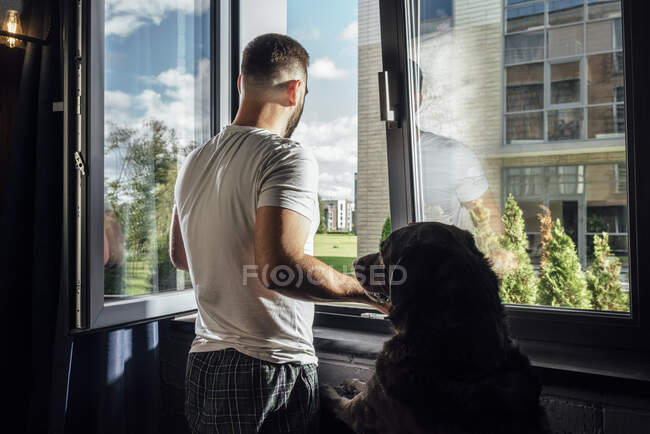 Metà uomo adulto guardando attraverso la finestra da cane a casa — Foto stock