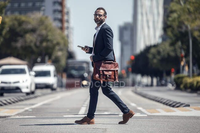Professionista uomo d'affari con tracolla e telefono cellulare in strada — Foto stock