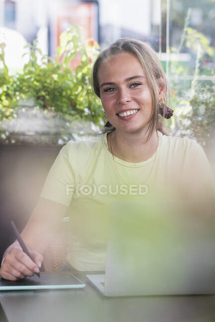 Female student with laptop and graphic tablet at cafe table — Stock Photo