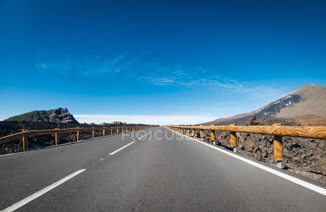 Scenic view of empty road amidst mountains on sunny day — Stock Photo