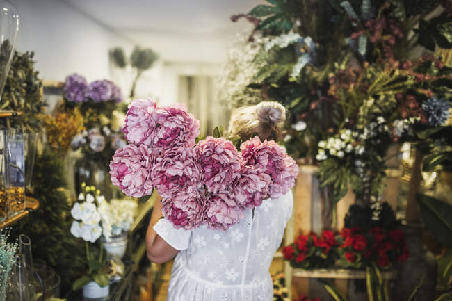 Жіночий флорист несе рожеву купу квітів, працюючи в магазині. — стокове фото