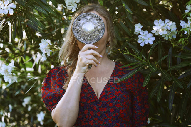 Femme tenant miroir devant la plante à fleurs — Photo de stock