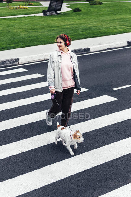 Donna sorridente con Jack Russell Terrier che attraversa la strada — Foto stock