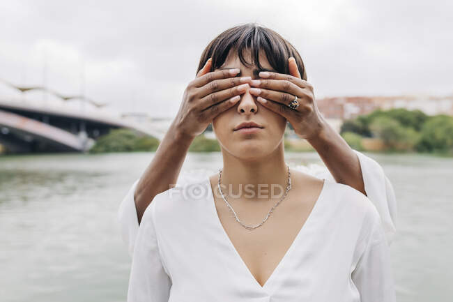 Взрослая женщина закрывает глаза подруге на берегу озера — стоковое фото
