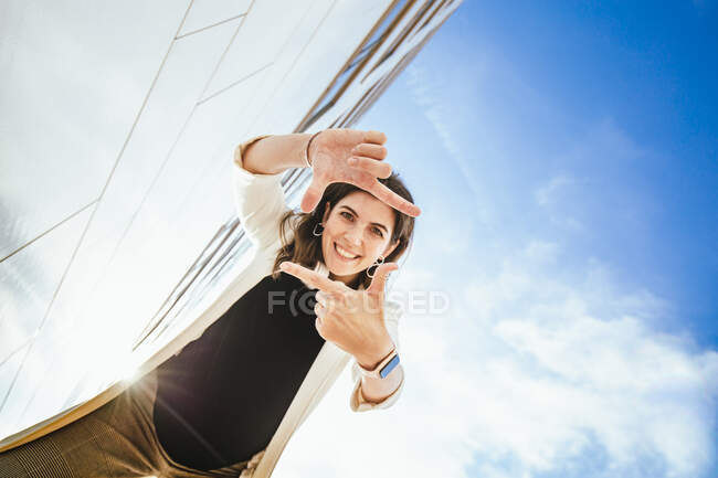 Smiling female freelancer making finger frame during sunny day — Stock Photo
