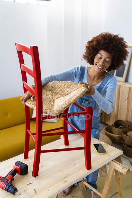 Junge Afrofrau repariert Stuhl im Wohnzimmer — Stockfoto