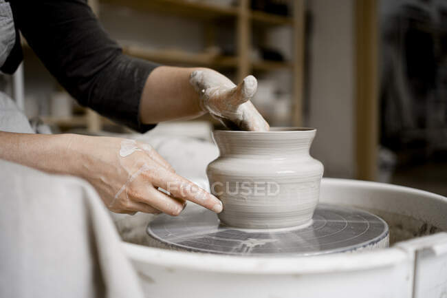 Young craftswoman making flower pot on pottery wheel — Stock Photo