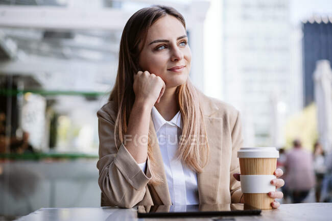 Nachdenkliche Geschäftsfrau mit Einweg-Kaffeetasse auf der Terrasse — Stockfoto