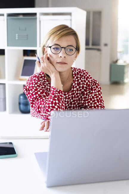 Pensativo profesional femenino mirando portátil en la oficina - foto de stock