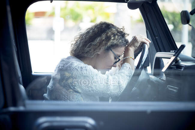 Stanco donna matura con i capelli ricci seduto in auto — Foto stock