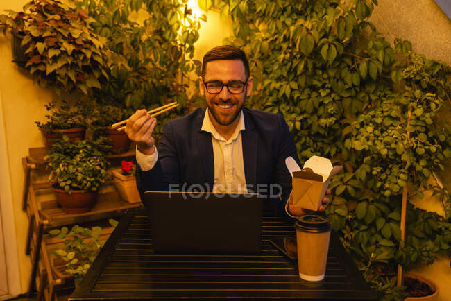 Sourire professionnel masculin dîner tout en travaillant tard dans le balcon du bureau — Photo de stock