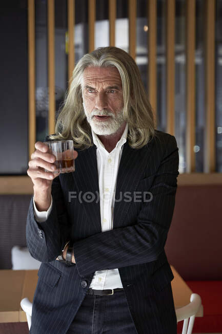 Male professional holding whiskey glass while standing at hotel cafe — Stock Photo