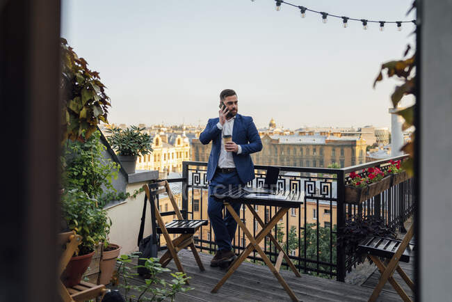 Бизнесмен разговаривает по смартфону на офисном балконе — стоковое фото
