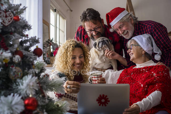 Сім'я з собакою, яка відвідує відеодзвінок через ноутбук. — стокове фото