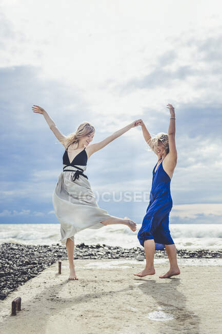 Daughter holding hand of mother while dancing on pier — Stock Photo